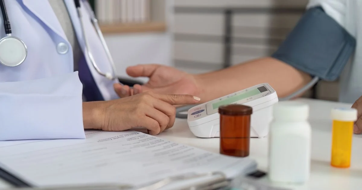 Doctor measuring patient’s blood pressure with digital monitor.